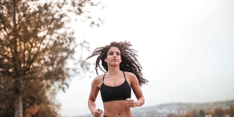 Determined woman in red leggings jogging along a scenic riverside path, embracing fitness outdoors.