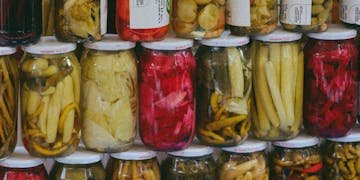 Vibrant display of pickled vegetables in jars at a traditional Turkish market.
