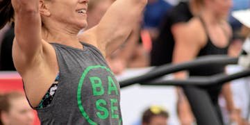 Focused female athlete lifting weights at an outdoor competition showcasing strength and determination.