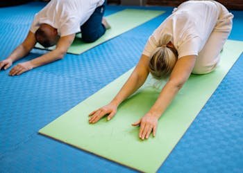 Senior adults stretching on yoga mats inside a gym, promoting health and fitness.